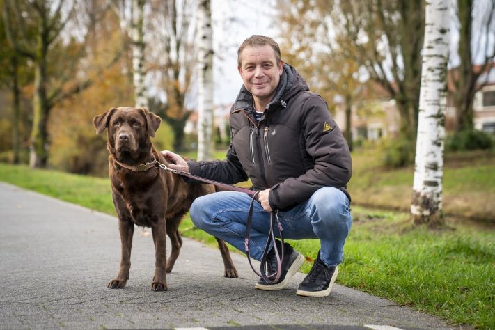 Jan op de foto met zijn hond, een bruine labrador