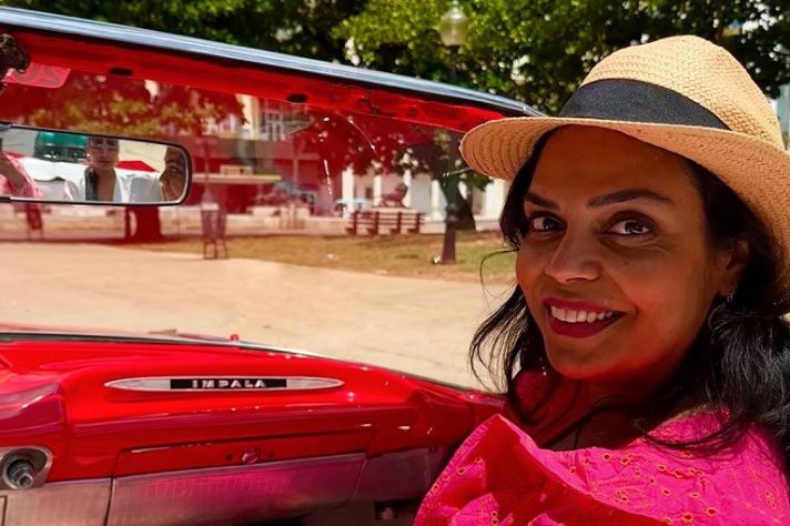 Een foto van Vandana met een zomerhoed op, in een auto, tijdens een vakantie