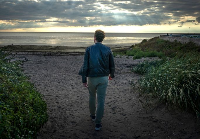 Een foto van Bastiaan op het strand, gefotografeerd vanaf de achterkant