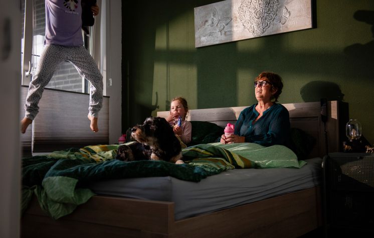 Ee foto van Anita met haar kleinkinderen en hondje, in bed